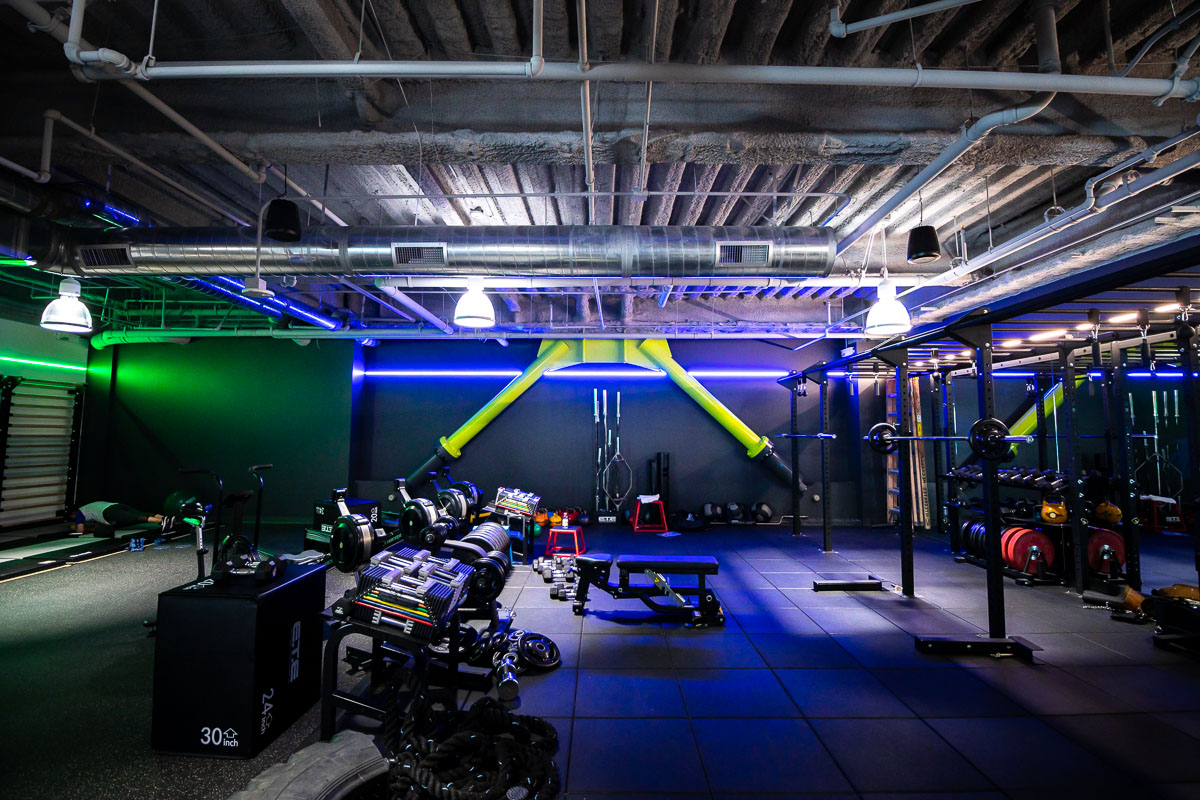 The strength training floor at TRIFIT LA lit in blue and green