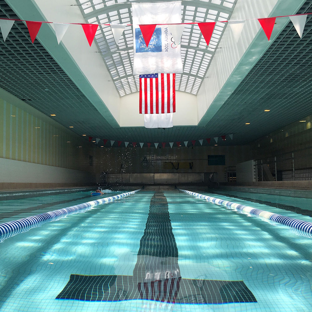 The indoor 25-yard lap pool at TRIFIT LA with lane ropes and pennants overhead